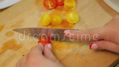 一个女人正在用一把刀在木板上切一个黄色和红色的樱桃番茄。 时光飞逝。